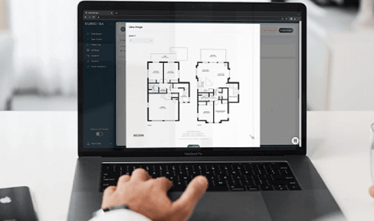 A laptop displaying floor plans for a home on a white desk